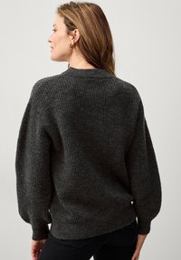 Donkergrijze trui met een gestructureerd breisel, ronde halslijn en pofmouwen. De achterkant toont een relaxte pasvorm en subtiele zoomdetails.