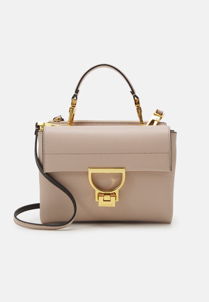 Beige lærveske med en strukturert form, gullfargede detaljer, avtagbar crossbody-rem og en distinkt frontlås.