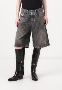 Jeanshorts i falmet svart med rett snitt, kombinert med knelende svarte støvler i falsk krokodillelær med glidelås.