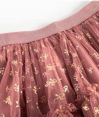 Różowa tiulowa spódnica z teksturowanym elastycznym pasem, zdobiona złotymi wzorami w kokardki oraz warstwowym wykończeniem z falbanek na dolnej krawędzi.