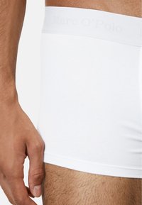 Weiße Baumwoll-Boxershorts mit einem weichen elastischen Bund, auf dem der Markenname "Marc O'Polo" dezent in Hellgrau geprägt ist. Glatte Textur.