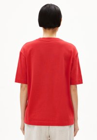 Rode katoenen T-shirt met korte mouwen, ronde hals, rechte zoom en een losse pasvorm. Eenvoudig ontwerp zonder zichtbare patronen of accenten.