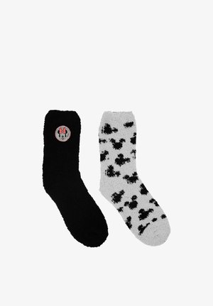 Black fuzzy sock with Minnie Mouse patch and gray fuzzy sock with black Minnie Mouse head patterns, arranged side by side.