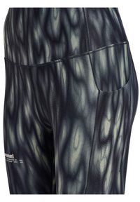 Close-up van donker gemêleerde sportleggings met een zijzak en een klein wit merkembleem bij de dij.