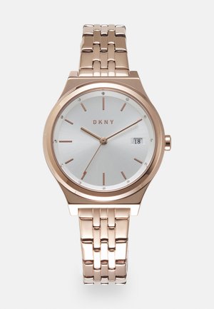 Rose gold DKNY watch with a silver dial, minimalist hour markers, and crystal accents. Features a metal link bracelet and date display.