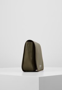 Borsa a tracolla in pelle verde oliva con una forma strutturata, cuciture visibili lungo i bordi e un piccolo dettaglio del logo argentato sul davanti.