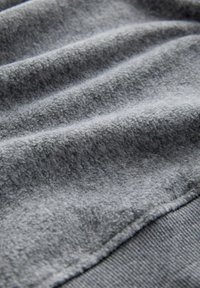 Pelēka vilnas auduma ar mīkstu tekstūru un redzamām rievām. Izceļas ar gludu malu un smalku spīdumu, kas uzsver tā grezno virsmu.