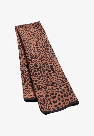 Tissu brun plié avec des taches irrégulières noires de léopard et un ourlet noir sur fond blanc.