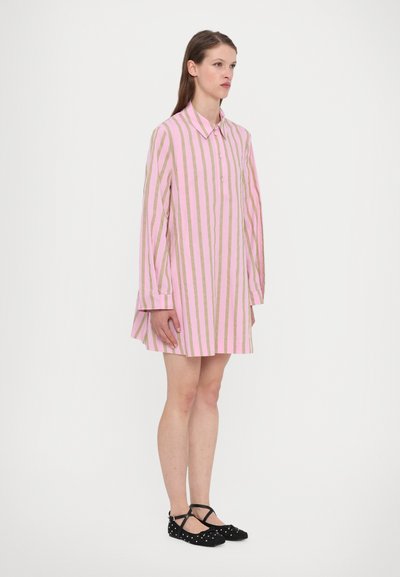 Pink and gold striped shirt dress with a pointed collar, button front, and long sleeves. Paired with black flats featuring white polka dots.