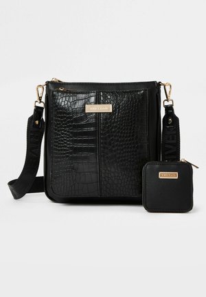 Sort taske i imiteret læder med krokodillemønster, gulddetaljer og justerbar rem. Indeholder en matchende lille pung med lynlås og logodetalje.