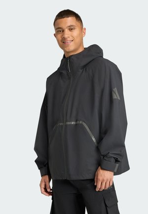 Black waterproof jacket with a hood, featuring reflective accents and a front zipper. The design includes a relaxed fit and side pockets.