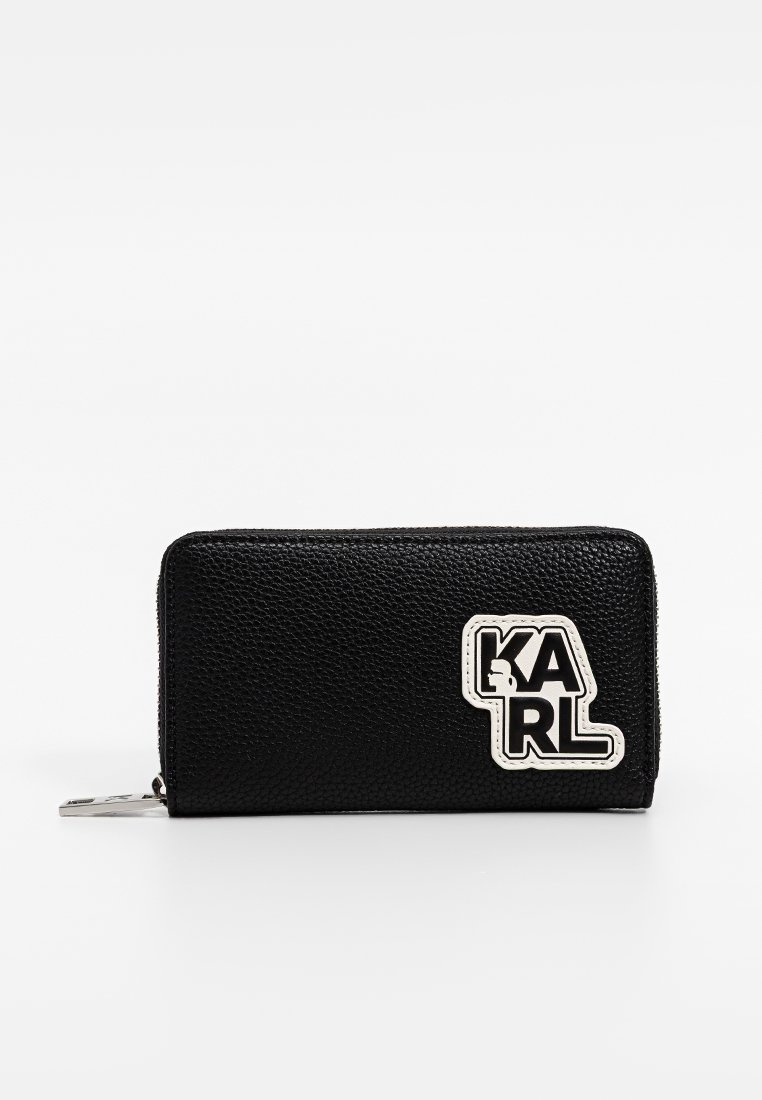 Cartera de cuero negro con superficie texturizada y el logo blanco "KARL" en la parte frontal. Cierre con cremallera y herrajes plateados.