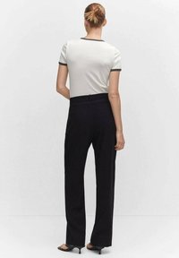 Witte shirt met korte mouwen en zwarte accenten, gecombineerd met hoge zwarte broek met een rechte snit en een gladde textuur.
