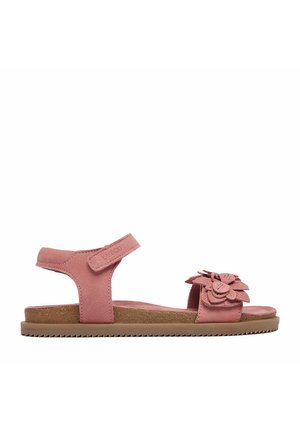 Sandalo piatto in suede rosa con cinturino alla caviglia in velcro e dettaglio floreale decorativo sul cinturino delle dita, abbinato a una suola marrone chiaro.