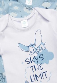 Body neonato bianco con design di Dumbo e testo "IL CIELO È IL LIMITE" accanto a un body azzurro chiaro con motivi di nuvole e bottoni.