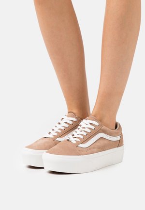 Light brown suede sneakers with a white wave design, white laces, and white platform sole. The design features a smooth texture.