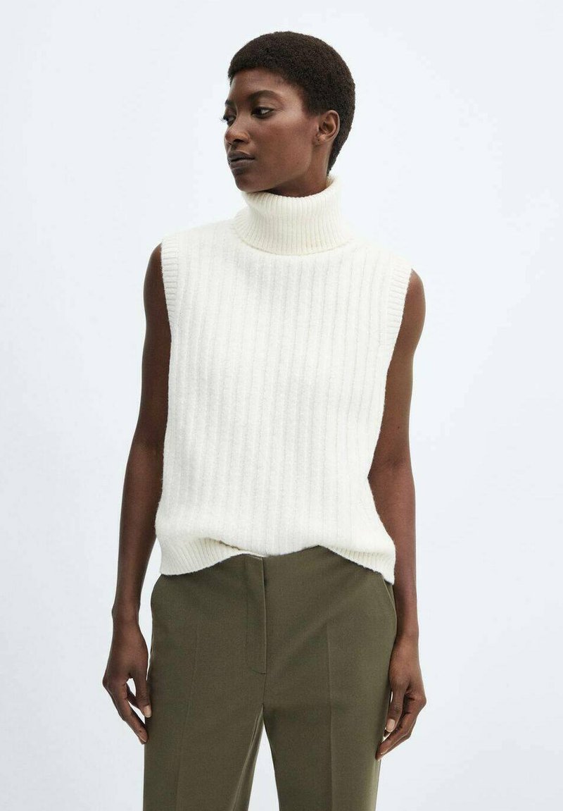 Maglione senza maniche a collo alto in tessuto a coste abbinato a pantaloni verde oliva; linee pulite, tessuto morbido e vestibilità rilassata.