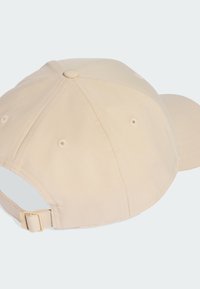 Beige baseballová čepice vyrobená z měkké tkaniny, s prohnutým kšiltem, šitými detaily a nastavitelným páskem na zadní straně.