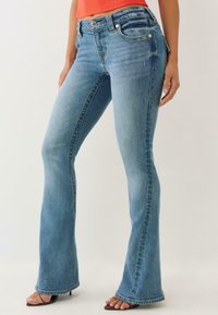 Uitlopende blauwe denim jeans met een medium taille, voorzien van een vijf-pocket ontwerp, lichte slijtage en een lichte vervaging langs de dijen.