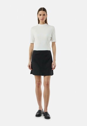 Witte geribde top met korte mouwen, gecombineerd met een zwarte A-lijn rok. Zwarte instappers maken de outfit compleet en tonen een minimalistisch ontwerp.