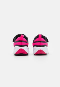 Scarpe da ginnastica nere e rosa con suola imbottita, dettagli rosa e tomaia in tessuto texturizzato con un'etichetta di pull sul tallone.