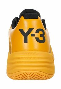 Gelbe Sportschuh mit strukturiertem Obermaterial, Y-3 Branding auf der Rückseite und einer gemusterten Gummisohle. Schwarze Akzente am Kragen.