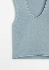 Vaaleansininen neulottu hihaton paita, jossa on syvä, avara kaula-aukko, suorat reunat ja rakenne, joka on hieman joustava.