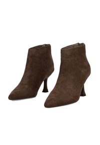 Botines de ante marrón con punta afilada y un diseño elegante. Presentan un tacón alto y delgado y un cierre con cremallera en la parte trasera.