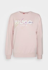 Růžová mikina z měkkého materiálu, s kulatým výstřihem, spadlými rameny a multicolor logem "Hugo 1993" na přední straně.