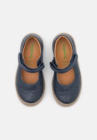 Zapatos de cuero azul marino con punta redonda, diseño ondulado y correa ajustable. Plantilla color canela con marca verde. Suela de goma.