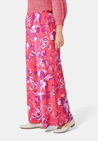 Pantalons larges à motifs floraux en rose vif avec des fleurs violettes et blanches. Dotés d'une taille élastique et d'une silhouette fluide.