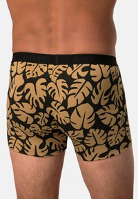 Černá boxerská trenýrky se vzorem velkého zlatého monstera listu; měkká tkanina s černým elastickým páskem, na kterém je nápis "JP1880."