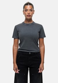 T-shirt grigio a maniche corte realizzato in morbido cotone, con colletto a girocollo e vestibilità rilassata, abbinato a jeans neri a vita alta con gamba larga.