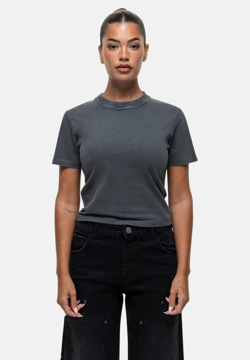 T-shirt grigio a maniche corte realizzato in morbido cotone, con colletto a girocollo e vestibilità rilassata, abbinato a jeans neri a vita alta con gamba larga.