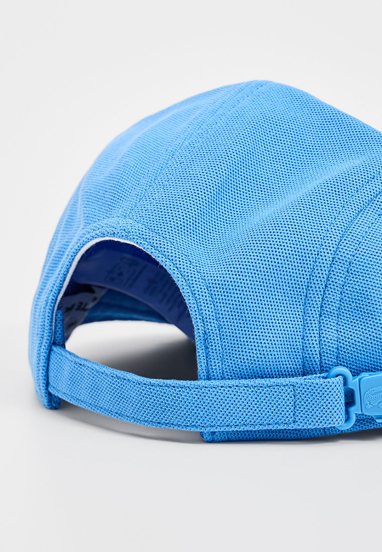 Lichtblauwe pet van gestructureerde stof, met een gebogen klep en een verstelbare band aan de achterkant met een plastic gespsluiting.