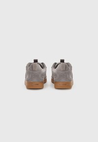 Gray suede sneakers with a tan rubber sole. Features a pull tab at the heel and textured accents on the collar.