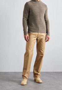 Bruine wollen trui met een ronde hals, gecombineerd met beige broek en tan instap schoenen. Gladde textuur, eenvoudig ontwerp zonder zichtbare patronen.