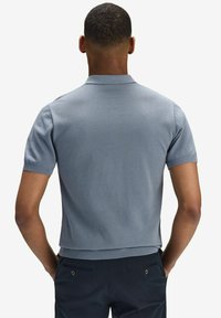 Kortärmad polo skjorta i ljusblått, strukturerad tyg med ribbad krage och ärmslut. Designad med en ren, strömlinjeformad silhuett.