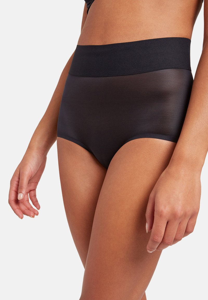 Högmidjade svarta underkläder som har ett mjukt, semi-genomskinligt tyg, ett brett elastiskt midjeband och en minimalistisk design utan synliga sömmar.