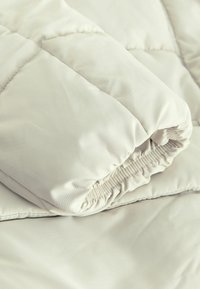 Svetlo béžová prešívaná deka s hladkým, jemným povrchom. Obsahuje elastický zberný otvor a plochý, nevylepšený povrch.