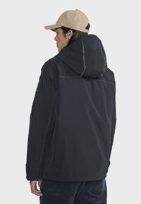 Veste imperméable noire avec capuche, dotée d'une finition mate et de coutures réfléchissantes. Manches ajustables et poches latérales incluses.