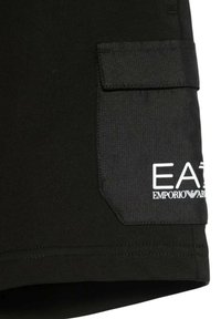 Pantaloni corti neri con una tasca testurizzata nera che presenta il logo bianco "EA7 Emporio Armani". Tessuto liscio con dettagli di cucitura pulita.