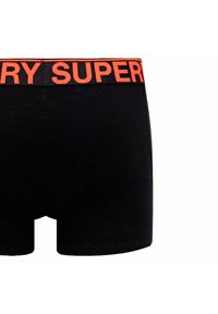Boxers noirs avec une taille élastique et le mot "SUPER" en grand orange. Tissu lisse avec un ajustement serré.