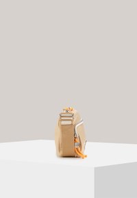 Borsa in tessuto color sabbia con zip laterale, dettagli in corda arancione e tracolla beige. Design compatto con una texture liscia e hardware minimale.