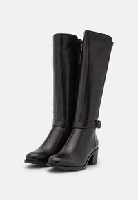 Bottes en cuir noir montant jusqu'au genou avec une finition lisse, un bout arrondi et un talon bloc. Comprend une sangle ajustable près de la cheville.