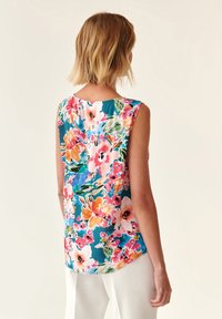 Haut sans manches à motif floral avec un fond turquoise vibrant, présentant de grandes fleurs roses, orange et vertes, fabriqué en tissu léger.