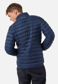Giacca puffer navy con design a baffle orizzontali, realizzata in materiale lucido, leggera, con colletto alto e logo semplice sulla schiena.