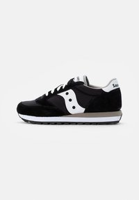 Černobílé tenisky Saucony s bílými tkaničkami, logem na boku a texturovanou podrážkou, zobrazené z vnější strany na jednobarevném pozadí.