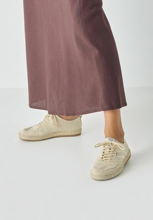 Beige lærreds sneakers med hvide striber, tekstiloverdel, gummisål og jutedetaljer i espadrillestil. Bruges med en lang, bordeaux nederdel.