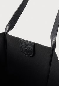 Melns tote soma ar faktūru ādas apdari, izturīgām rokturiem un sprādzes aizdari. Interjers ir vienkāršs un bez rotājumiem.